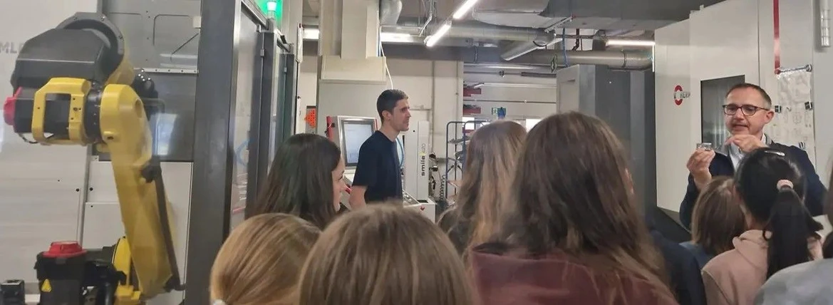 KNAUER: Figure 8 - Thomas Müller explains to the girls how CNC machines mill the housing for a pump head from a block of metal and why precision is crucial in this process. On the left is one of the robotic arms that continues working even at night, allowing employees to focus solely on daytime work and more demanding tasks.